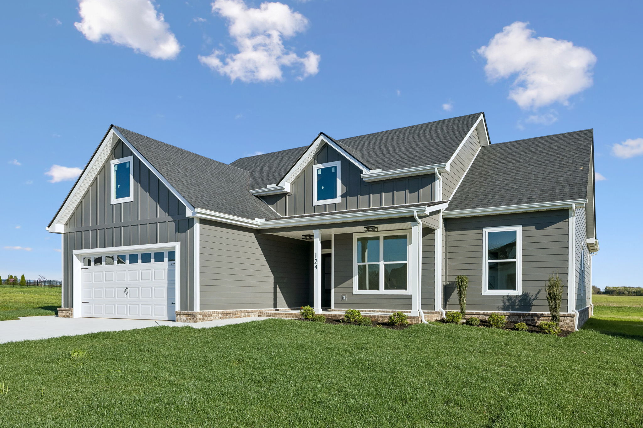 Modern gray house with a gable roof and large windows, set against a clear blue sky.