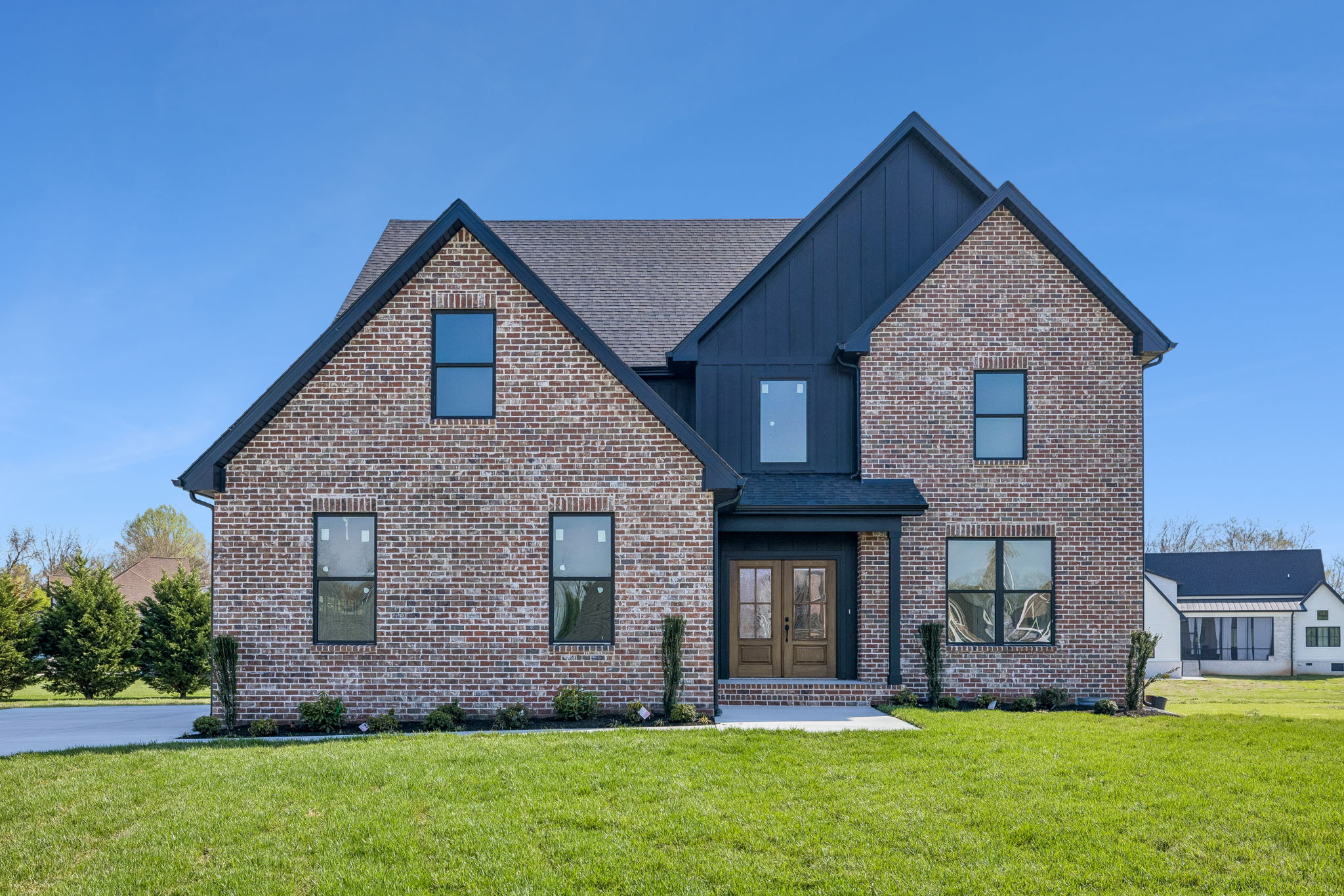 Beautiful brick house with manicured lawn and modern design elements under a clear blue sky.