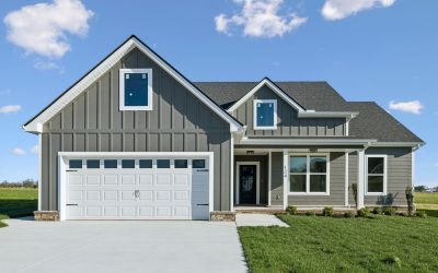 Modern gray house with white garage door, green lawn, and blue sky background.