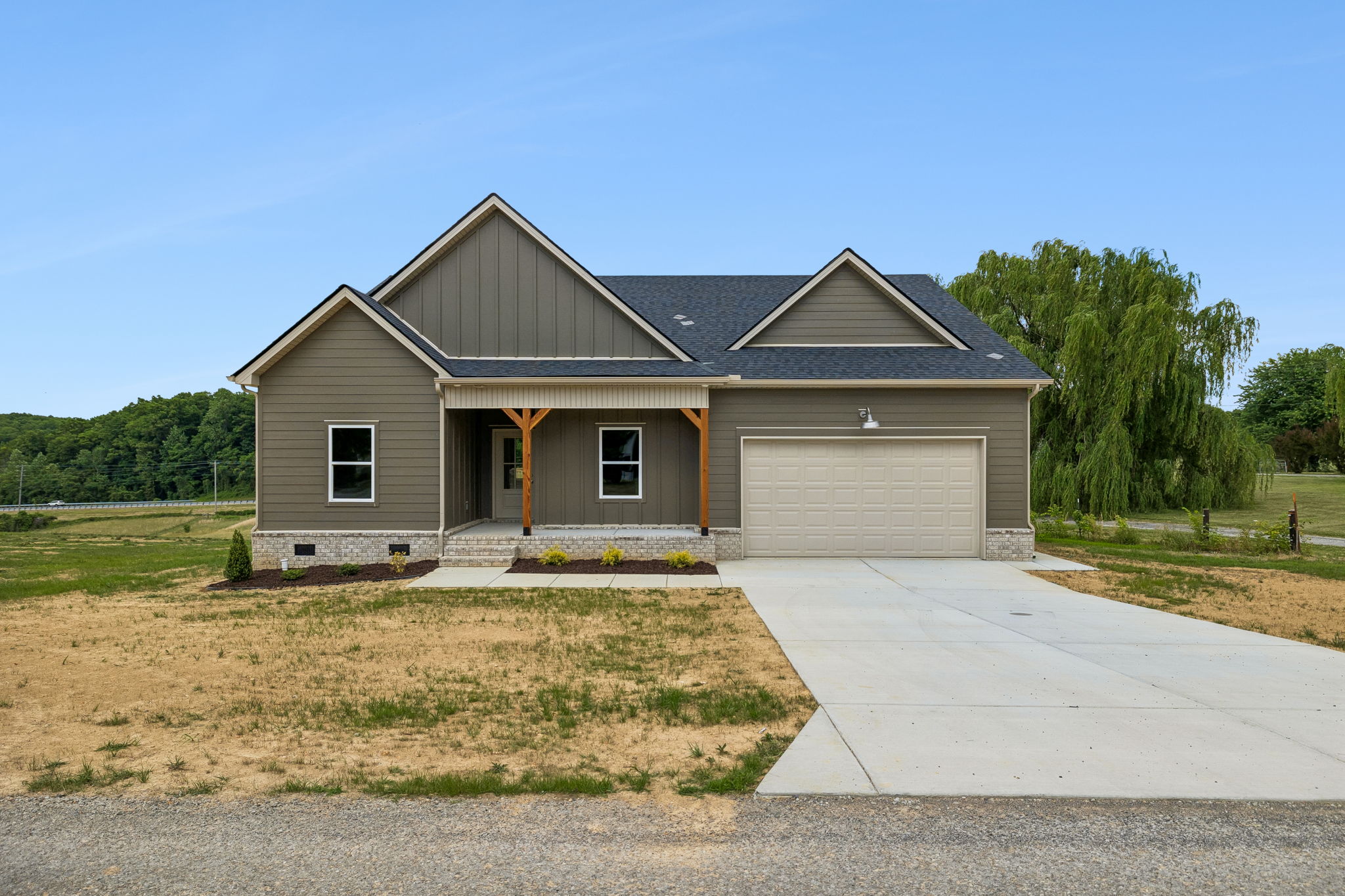 Modern single-story house with gray siding and attached garage, set in a rural landscape.