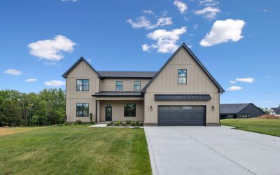Modern two-story home with gabled roof, spacious lawn, and blue sky background.