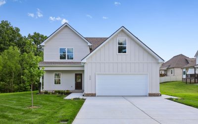 Modern suburban house with two-car garage and manicured lawn under clear blue sky.