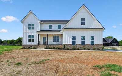 Front view of a white modern farmhouse with brick accents and a large front yard.
