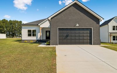 Modern single-story house with black brick facade and white siding, spacious driveway.